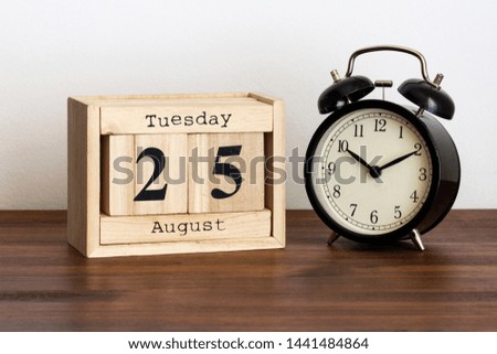 Wood calendar with date and old clock. Tuesday 25 August
