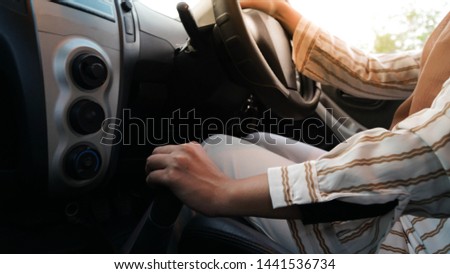 portrait of a Muslim hijab Woman turning on her car air conditioning system while driving a car