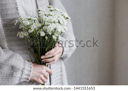 photo of young woman holding white flowers with green stem in her hands