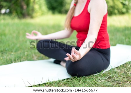 50 years old woman practice yoga on mat outdoors in a park on a grass.