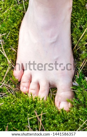 girl stands bare feet on the moss in the morning sun