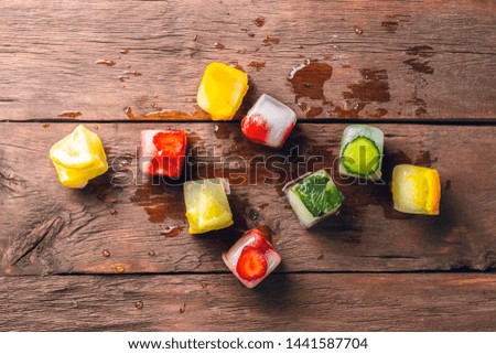Ice cubes with fruit on wooden background. The concept of hot summer dessert. Flat lay, top view