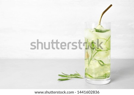 Glass of refreshing cucumber lemonade on table against light background, space for text. Summer drink