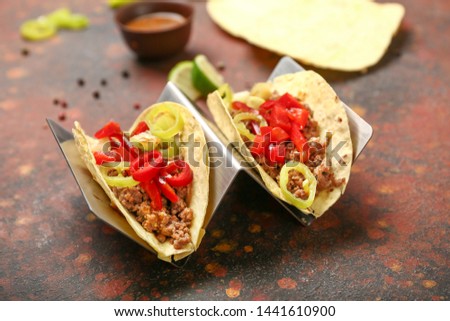 Stand with tasty fresh tacos on grunge background