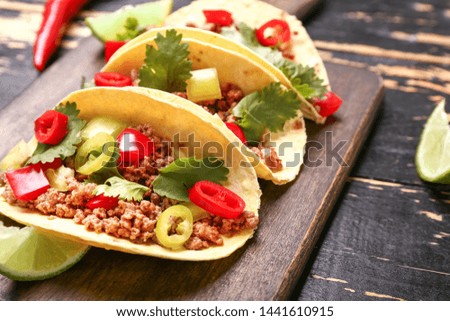 Board with tasty fresh tacos on wooden table, closeup