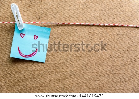 Sticky note with hand drawn a funny smiley face pin on cork board, with copy space. Love for Valentine's day concept.