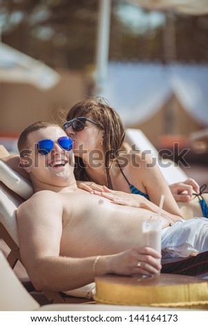 Relaxed happy couple sunbathing together at swimming pool in summer