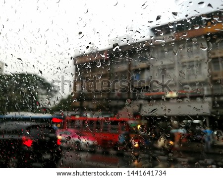 Raindrops on the car window and unclear​ picture of the traffic in the town
