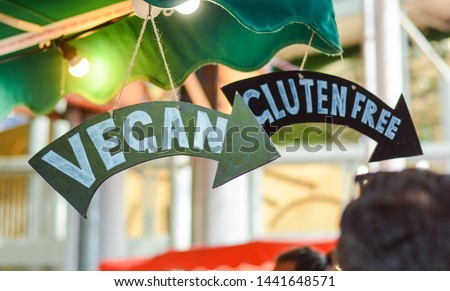 'Vegan' and 'Gluten Free' signs pointing to the food on display Royalty-Free Stock Photo #1441648571