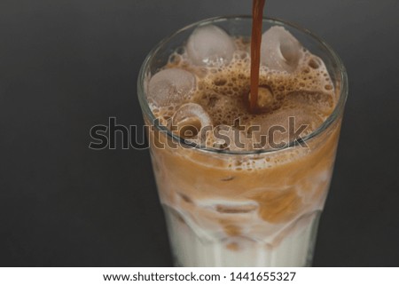 A large transparent glass filled with cold summer drink Latte with ice cooked in a third wave coffee shop is photographed on a gray, isolated background, photo for the menu