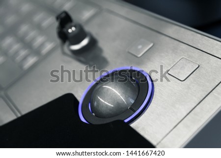 Industrial control panel made of gray metal with blue trackball and security lock key, close up photo with soft selective focus Royalty-Free Stock Photo #1441667420