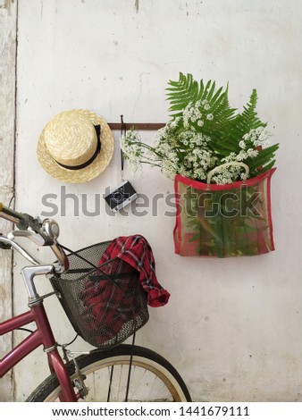 Bouquet of wild white flowers and fern leaves vintage bag and straw hat on white wall background of old cottage