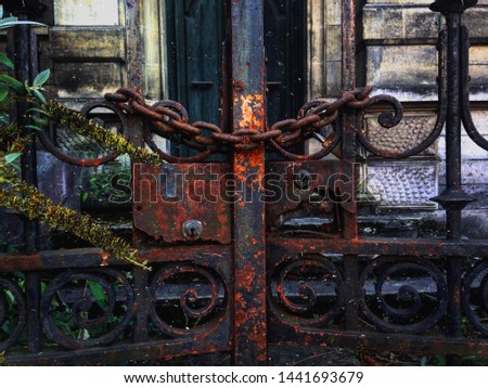 An old typed photo of a rusty gate closed by a chain