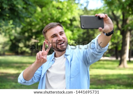 Happy young man taking selfie in park