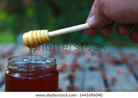 honey flowing from spoon and honey jar on table Royalty-Free Stock Photo #1441696040