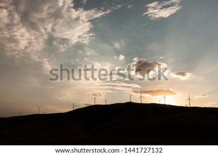 silhouettes of wind turbine running in wide angle sunset scene