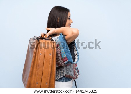 Young woman over isolated blue wall holding a vintage briefcase
