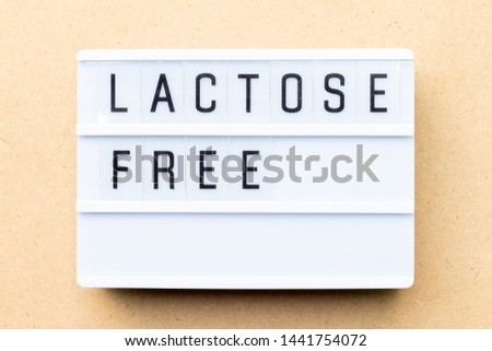 White lightbox with word lactose free on wood background