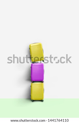 Colorful suitcases stacked, on pastel color background, minimal travel vacation creative concept.