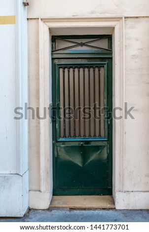 Geometry of antique door lattice with polished surface painted in deep green color. Facade of old building in Paris France. Vintage doorway and stone wall of classic architecture house. Travel Europe.