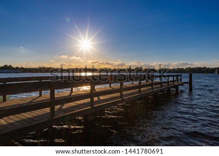 Summer landscape with wooden jetty (pier) extend into the Nieuwe meer (New lake) is in southwest of Amsterdam, Beautiful blue sky with golden sunlight before the sunset, Amsterdamse Bos.
