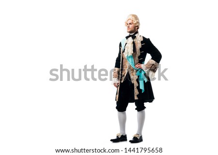victorian man in wig standing with hand on hip isolated on white  Royalty-Free Stock Photo #1441795658