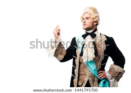 pompous victorian gentleman in wig standing with hand on hip and gesturing isolated on white  Royalty-Free Stock Photo #1441795700