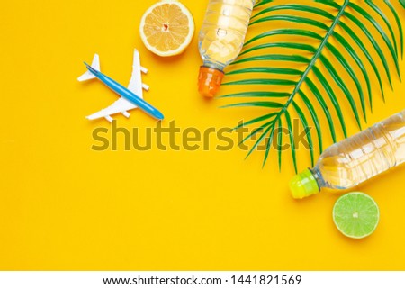 Tropic leaves and bottle l water on yellow background. Detox fruit infused water. 