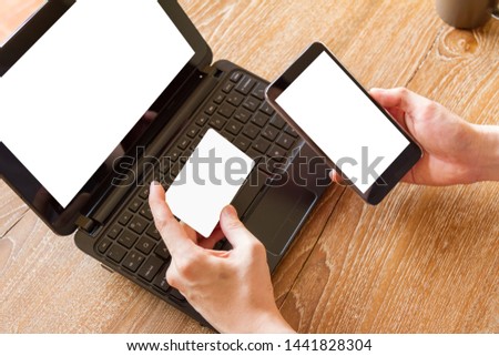 man holding credit card and using mobile phone and laptop computer with blank white screen for online shopping
