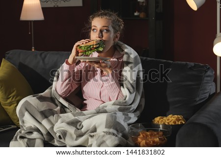 Beautiful young woman eating unhealthy food at night Royalty-Free Stock Photo #1441831802