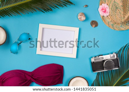 Photo frame with beach accessories, on the blue background. Top view.