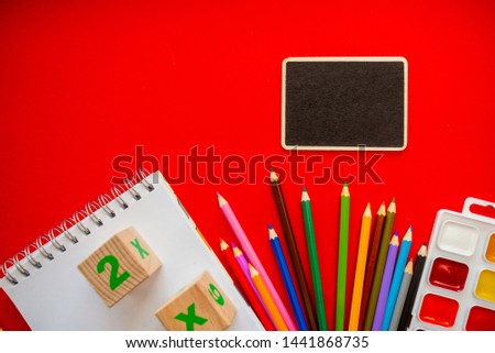 Back to school colorfull flatlay. Pencils notepad numbs a b c alphabet waterolors. Horizontal top view several objects above.