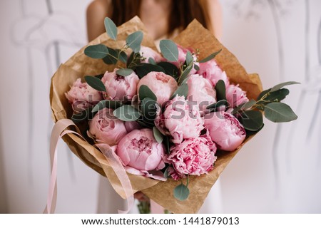 Very nice young woman holding big and beautiful mono bouquet of fresh pink peonies and eucalyptus, cropped photo, bouquet close up