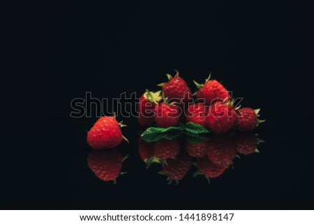 Beautiful fresh raspberry on a black glass table dark background.