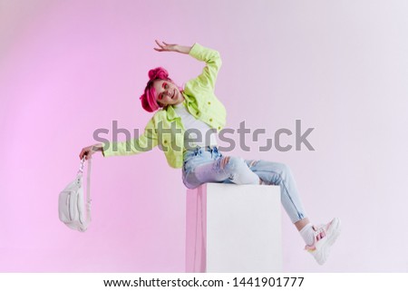 a woman in a green jacket is sitting on a pink hair stove