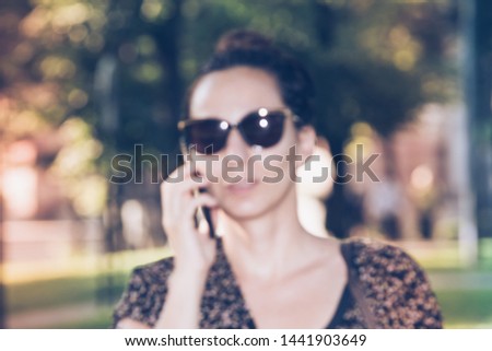 Woman speaking at cell phone while walking in park. Blurred image with vintage effect perfect for background.
