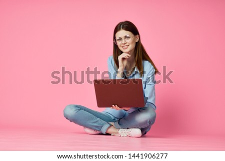 woman in shirt is sitting on the floor with a laptop