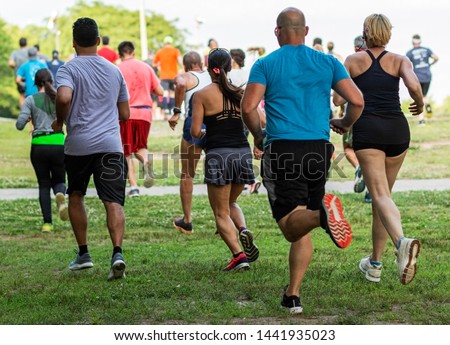 Runners running on grass away from the camera during a 10K summer series race at Sunken Meadow State Park. Royalty-Free Stock Photo #1441935023