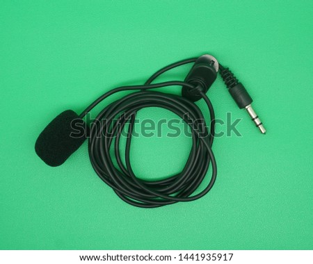 Portable Mini 3.5mm Tie Lapel Lavalier Clip-on mic on green screen, top view image.             