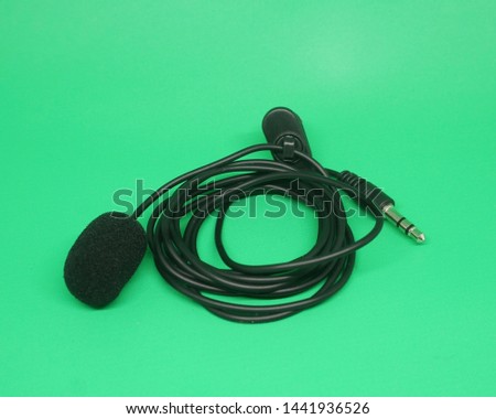 Portable Mini 3.5mm Tie Lapel Lavalier Clip-on mic on green screen, top view image.                        