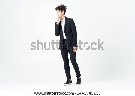 The guy in the classic suit in full growth on a light background looks to the side                       