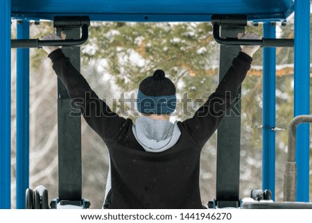 a man is pulled up on simulators in the Park in winter, despite the cold season