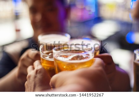Cheers! Clink glasses. Close-up pictures of hands holding a beer glass in a happy birthday celebration.