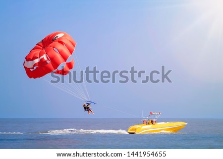 Parasailing - active form of recreation, in which a person is fixed with a long rope to a moving boat and thanks to presence of special parachute hovers through the air Royalty-Free Stock Photo #1441954655