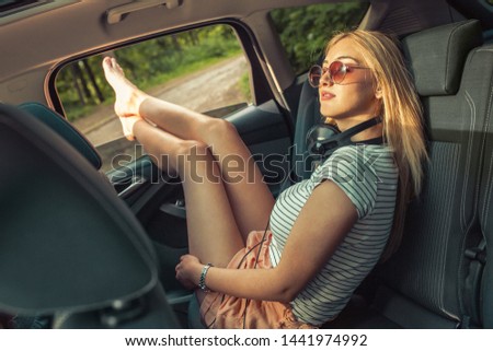 Casual look female  travel by car.She sitting on back seat relaxed and chills out.