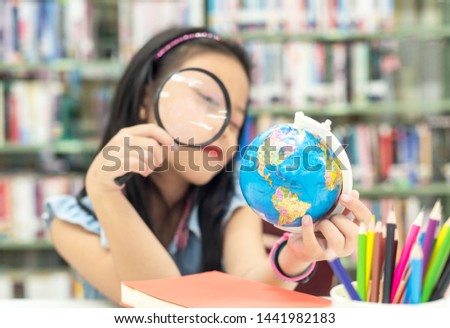 Student asian smiling child studying and education Earth Globe in library, select focus.   Education Concept

