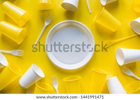 Disposable picnic white utensils for recycling on yellow. Trendy color Illuminating of the 2021 year.Top view. Flat lay. Space for text.