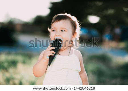 cute girl eating ice cream in a black horn of blue color, funny and beautiful