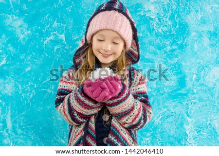 Girl dancing with snow. holiday of Christmas. Joy. Blue background. Portrait.