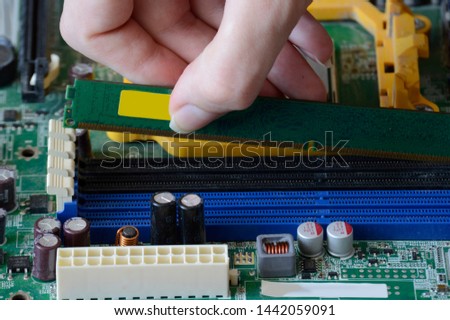 The process of fixing the green motherboard. Repairing an old chip on a computer against a dusty background.